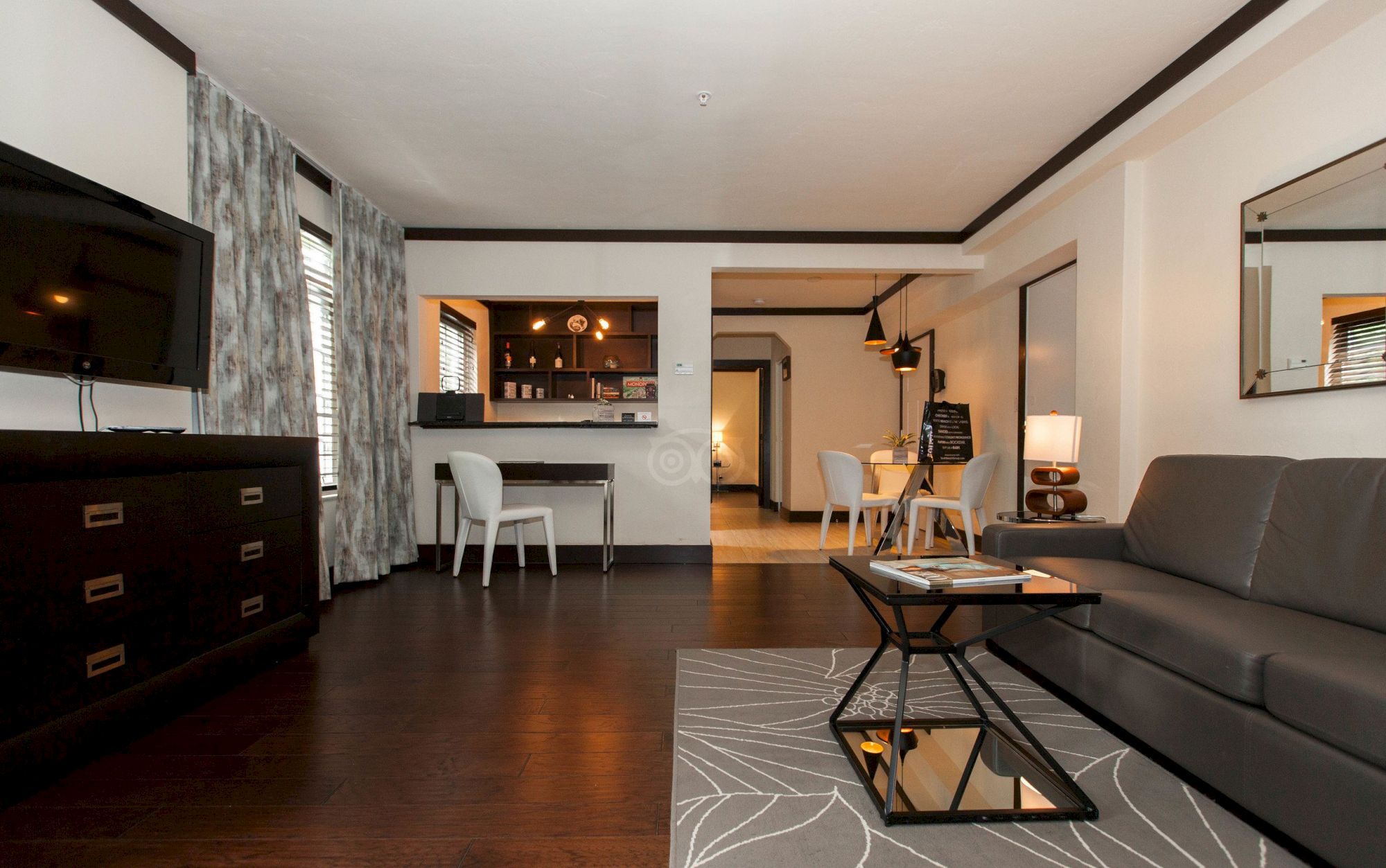 Modern living room and kitchen area with a gray sofa, coffee table, dining chairs, and pendant lights.
