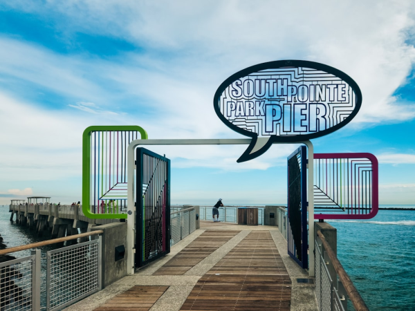 A seaside wooden pier at South Pointe Park Pier, with colorful railings and the ocean under a cloudy sky.