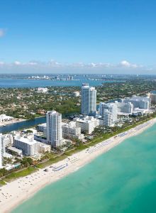 Aerial view of a coastal resort skyline with tall hotels and a sandy beach along turquoise water.