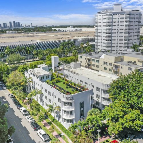 Aerial view of a sunny campus with white buildings, palm trees, and a large modern facility stretching across the grounds.